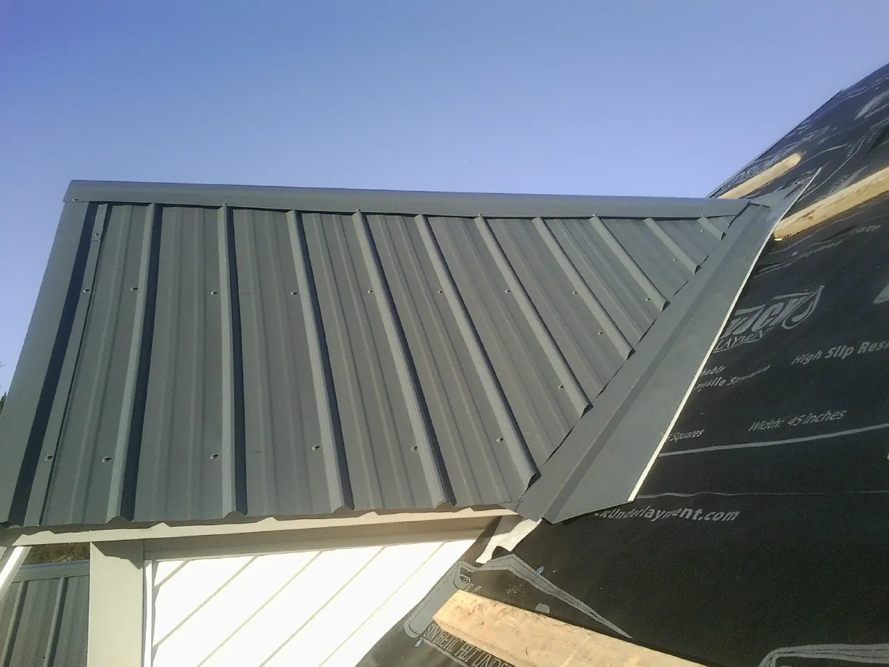 Gray metal roof panels going on over a garage gable in Oak Island