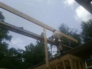Carpenter setting a ridge beam over a new addition frame — Ice Dam Removal by Roofing Brothers in Oak Island