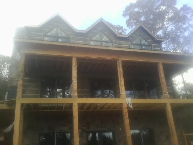 Dormers and porch framing on a large log home under construction — Roof Coating work by our crew in Oak Island