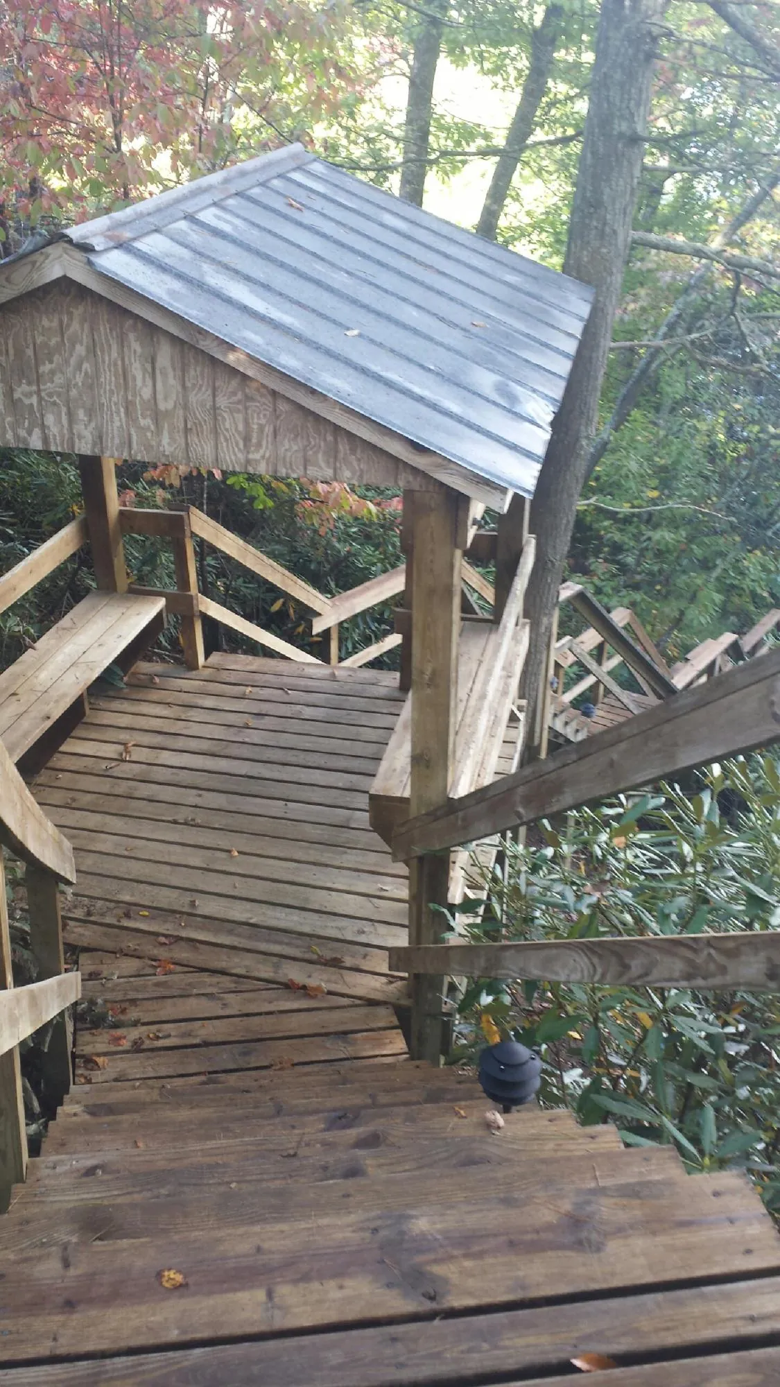 Metal roofed shelter over wooden steps on a wooded walkway — Skylight Repair & Installation work by our crew in Oak Island