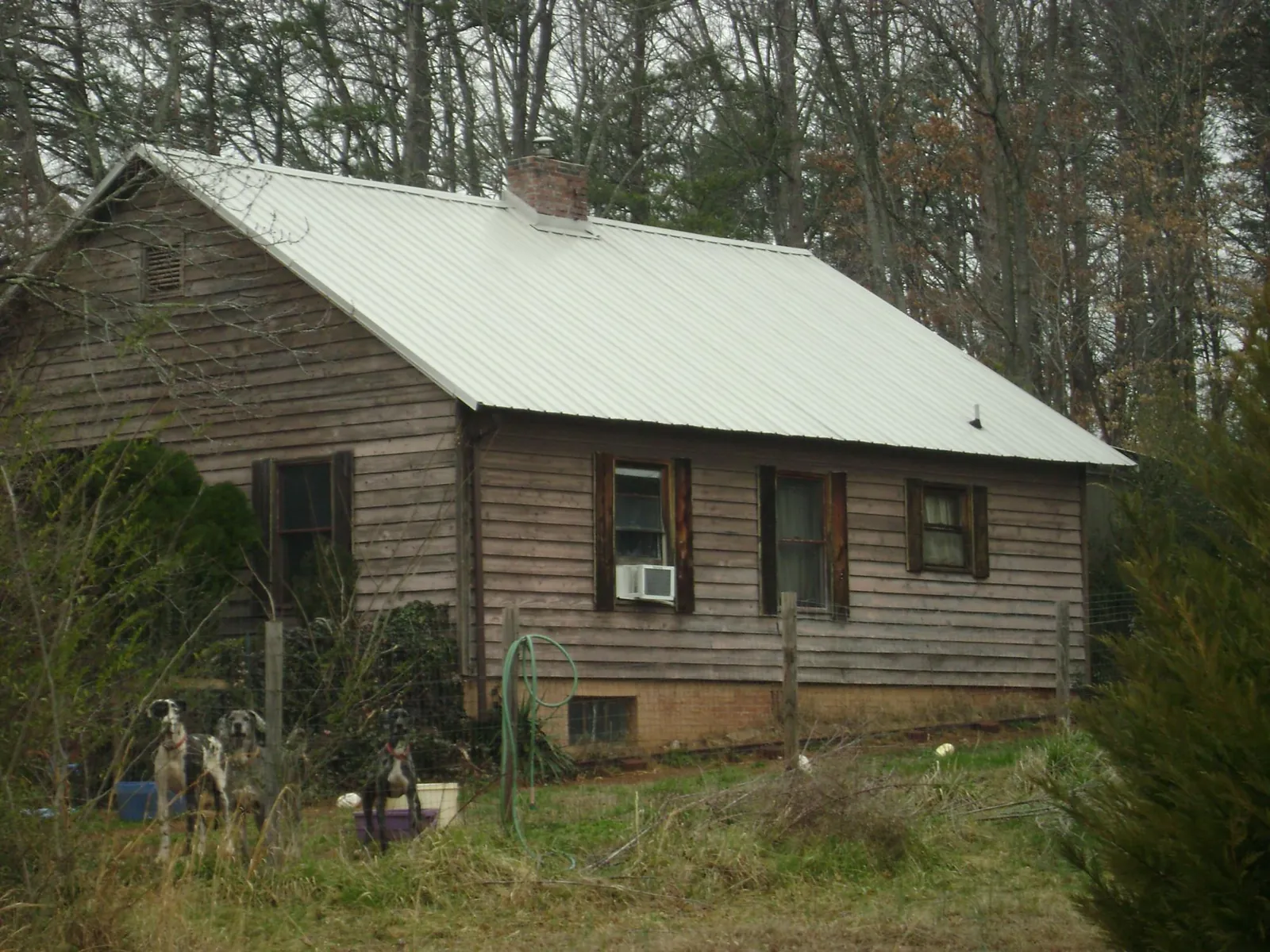 White metal roof on an old wood sided farmhouse, from a Metal Roof Installation job in Oak Island