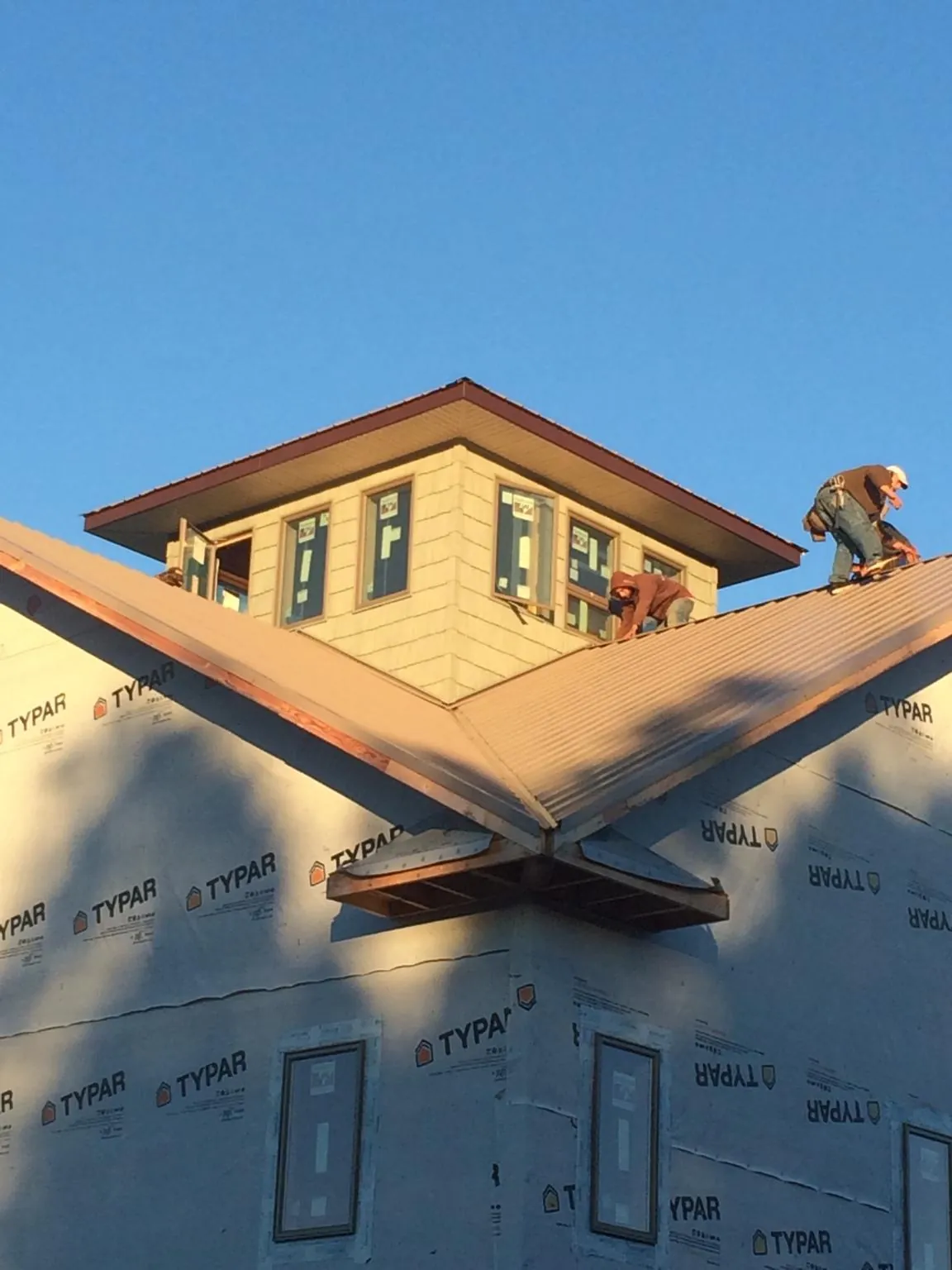 Roofers working around a rooftop cupola on a new metal roof at sunset — Roof Waterproofing in Oak Island by Roofing Brothers